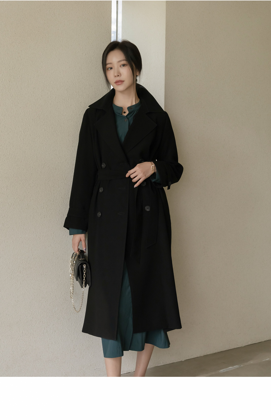 Woman in black trench coat over emerald green dress